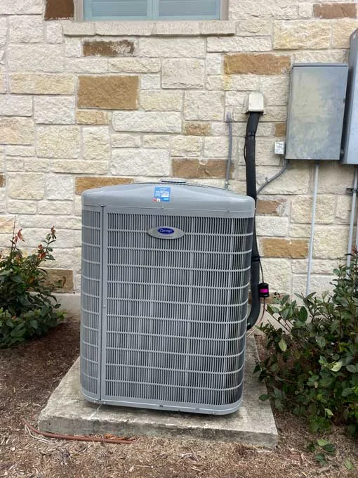 Carrier heat pump installed outside home in Boerne TX on concrete pad