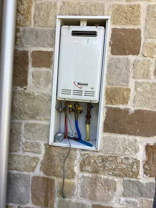 old exterior tankless water heater unit before replacement in Fredericksburg home