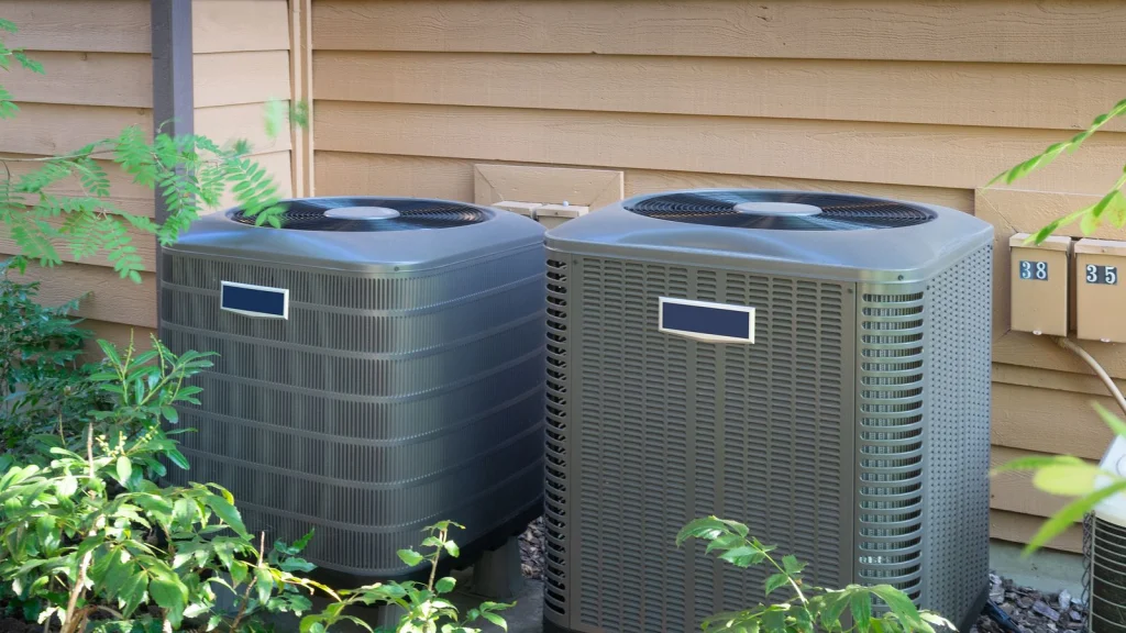 A dual air conditioner system outside a wood panel home.