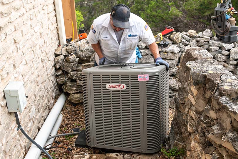 An HVAC technician installing a Lennox air conditioner