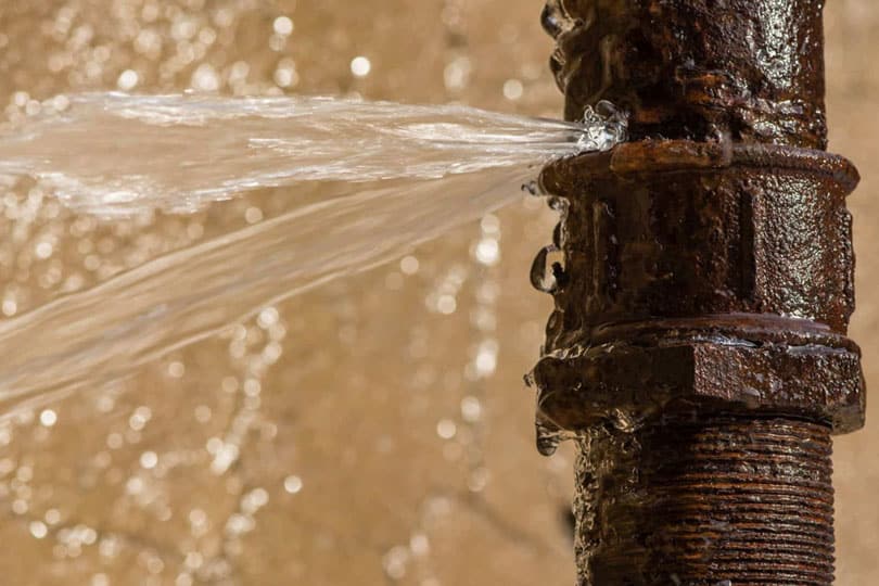 A detailed up close photo of a pipe bursting with water