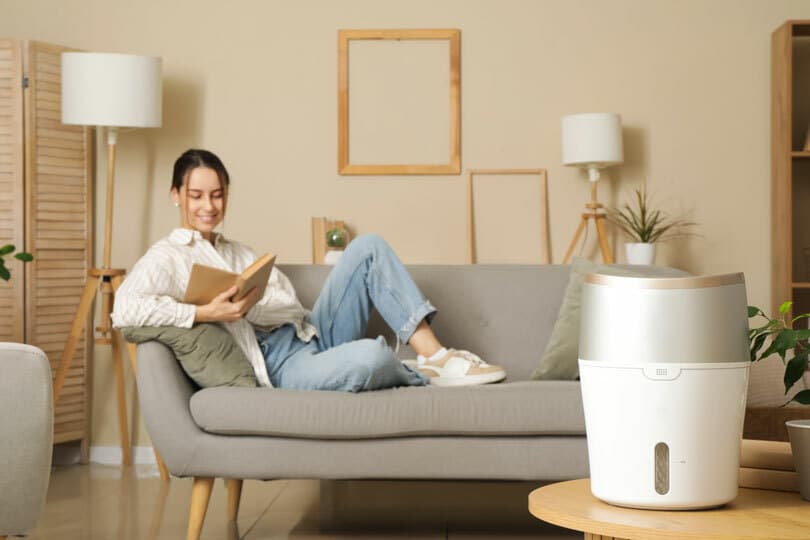 A person enjoying their space with a humidifier in the foreground.
