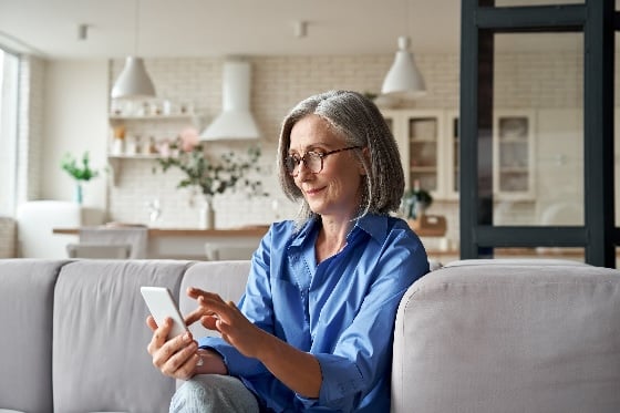 A photo of a woman on a couch using her phone
