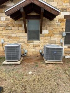 Two outdoor AC condenser units beside Mason, TX home