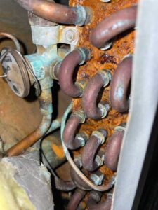 Corroded evaporator coil with visible refrigerant leak and rust buildup