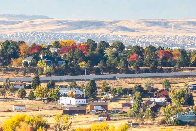 A landscape of rural homes in autumn with leaves changing and rolling hills