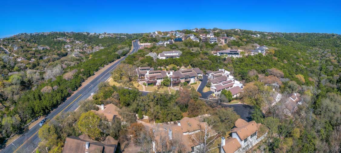 An aerial photo of a street winding up a hill in Texas with homes nestled along the way