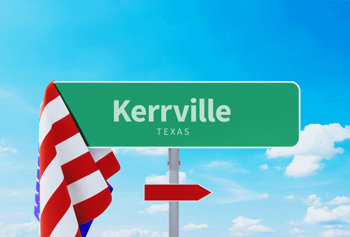 A street sign with Kerrville Texas on it and an American Flag hanging off of it