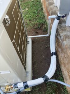 The compressor of a mini split system zoomed in on the refrigerant lines connecting to the head unit in the home
