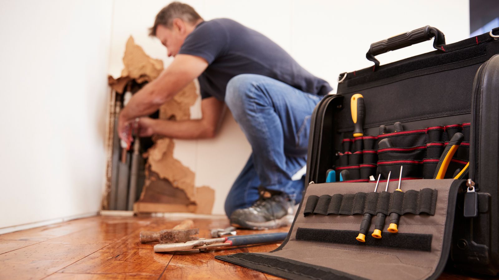 A plumber repairing leaks in a wall