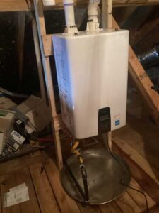 Navien tankless water heater mounted in attic with drain pan and gas connection